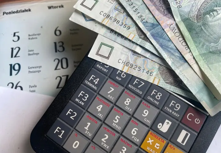 Kalkulator fiskalny z polskimi banknotami. Obok kalendarz z datami. Możliwe, że to przygotowanie do rozliczenia kwoty zmniejszającej podatek.