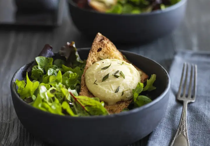 Salade fraîche avec une tranche de pain grillé et une quenelle de **chèvre chaud** garnie d'herbes.