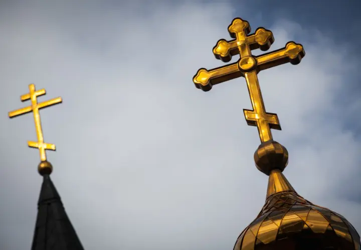 Złoty krzyż prawosławny na tle nieba. Drugi krzyż prawosławny widoczny w oddali.