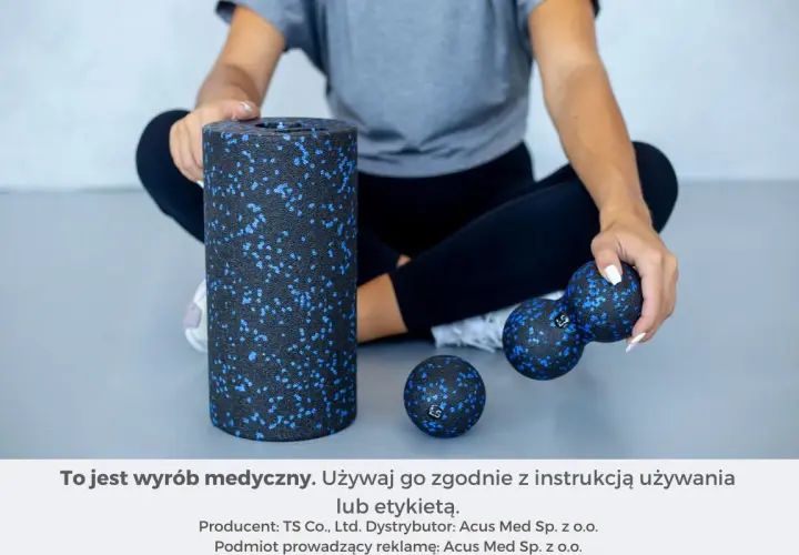 Kobieta siedzi obok wałka i piłek do rolowania mięśni.