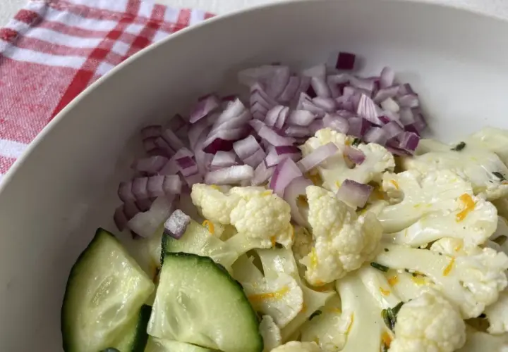 Ensalada de coliflor fresca con pepino y cebolla morada picada.