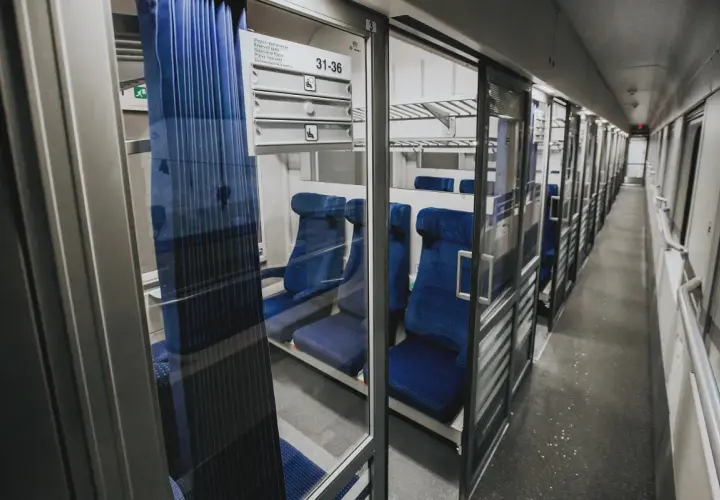 Wnętrze wagonu z przedziałami intercity 2 klasa. Puste, niebieskie siedzenia czekają na pasażerów.
