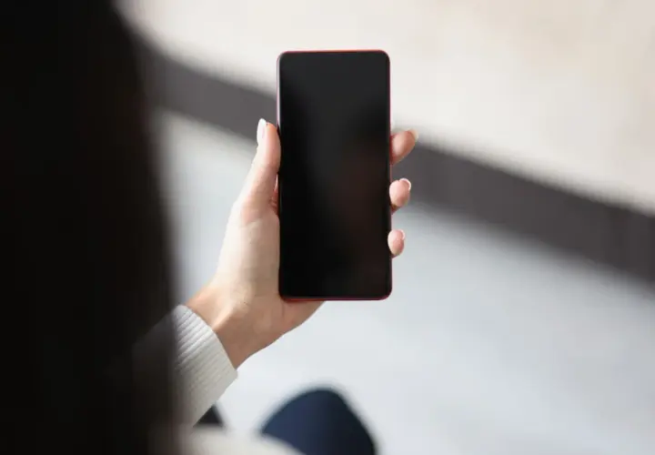 Dłoń trzyma telefon z czarnym ekranem. Czekam na powiadomienie.