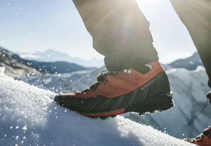 Pomarańczowe buty trekkingowe Mammut na śniegu, gotowe na wyprawę w Himalaje.