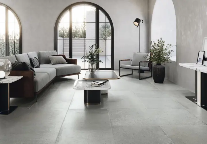Nowoczesny salon z szarymi płytkami pod ogrzewanie podłogowe, wygodną sofą i designerskimi meblami.