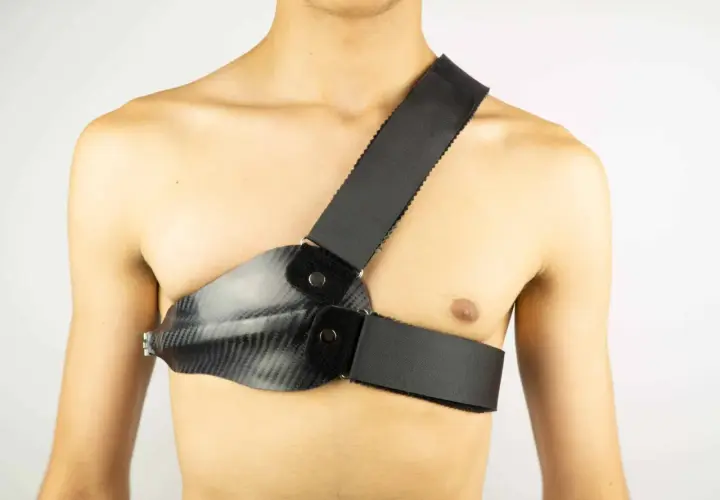 Person mit Carbon-Brustpanzer und Schultergurt. Der Rippenbuckel wird durch die Konstruktion gestützt.