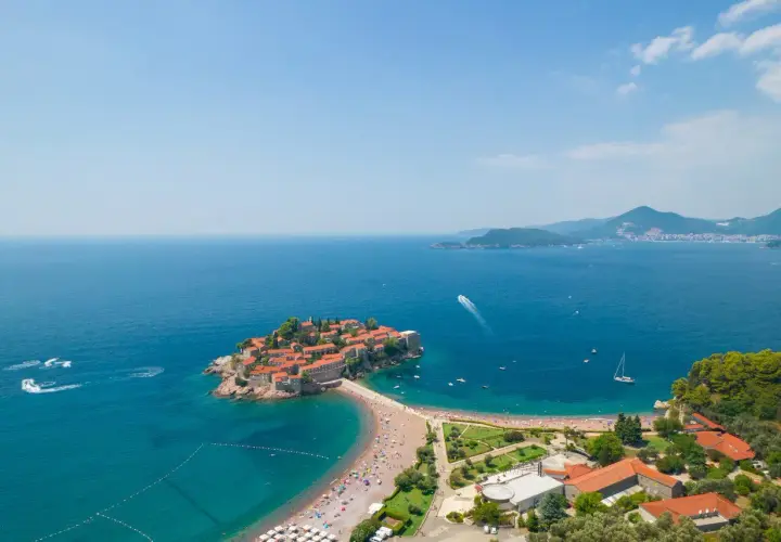 Sveti Stefan, perła czarnogórskiego morza, z malowniczą wyspą połączoną z lądem, otoczona turkusową wodą i zielenią.