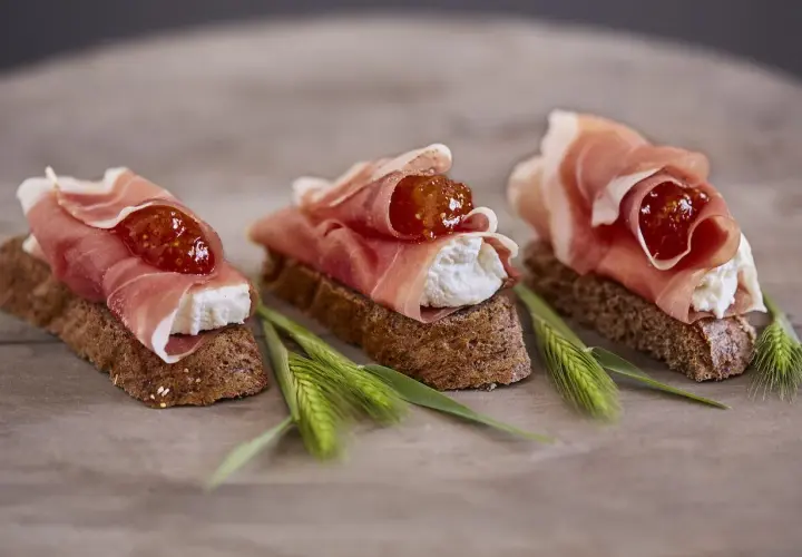 Drei kleine Brote mit Frischkäse, Feigenmarmelade und zartem **prosciutto schinken**.