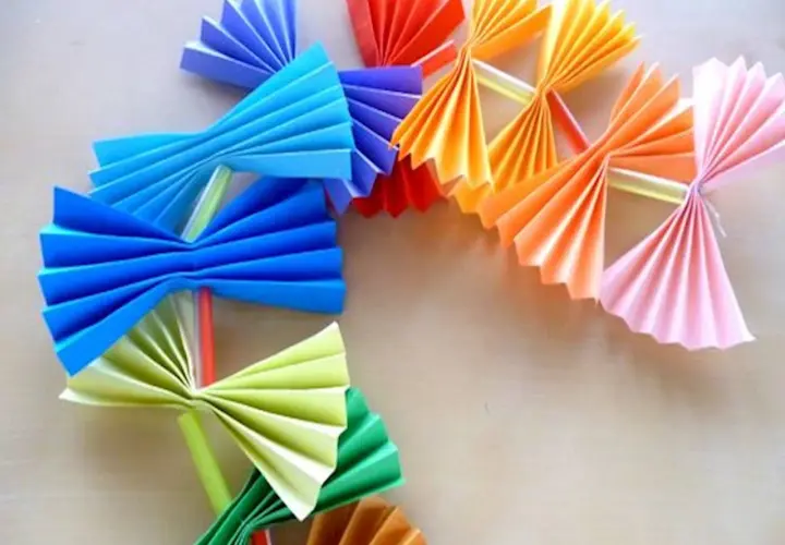 Kolorowy łańcuch choinkowy z papieru, wykonany techniką origami. Wesołe ozdoby w kształcie wachlarzy i kokardek.
