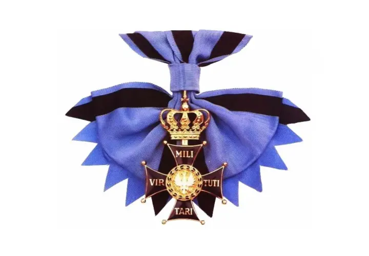 Złoty krzyż z koroną i wstęgą, symbol najwyższego odznaczenia wojskowego Virtuti Militari.