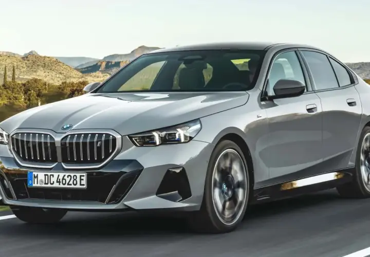 Szare BMW 540d jedzie po drodze na tle górskiego krajobrazu.