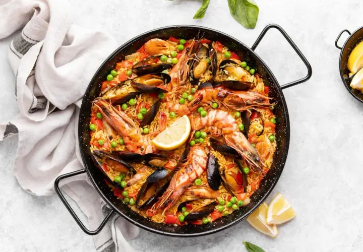 Paella royale aux crevettes et moules, garnie de pois et de citron. Quel vin avec la paella royale ? Un vin blanc sec et fruité, ou un rosé léger.