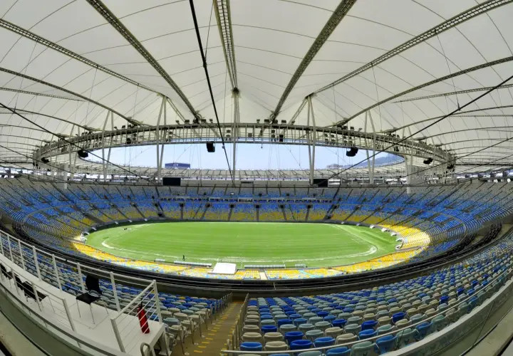 Pusta Marakana, stadion w Rio de Janeiro, z zieloną murawą i niebiesko-żółtymi trybunami pod białym dachem.