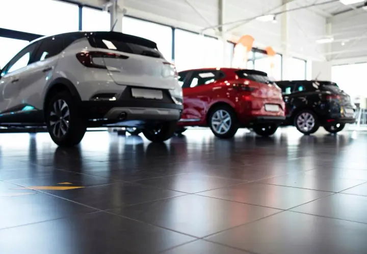 Tre auto, bianca, rossa e nera, in un concessionario. La valutazione autoscout è facilitata dalla vista posteriore dei veicoli.