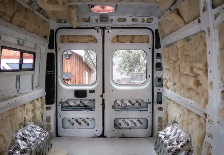 L'isolation d'un camping-car en cours, murs et plafond recouverts de laine de roche et de feuilles d'aluminium.