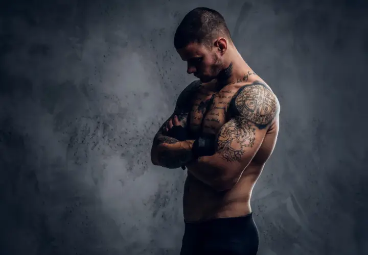 Mężczyzna z licznymi tatuażami na ciele, które tworzą jego drugą skórę po tatuazu.