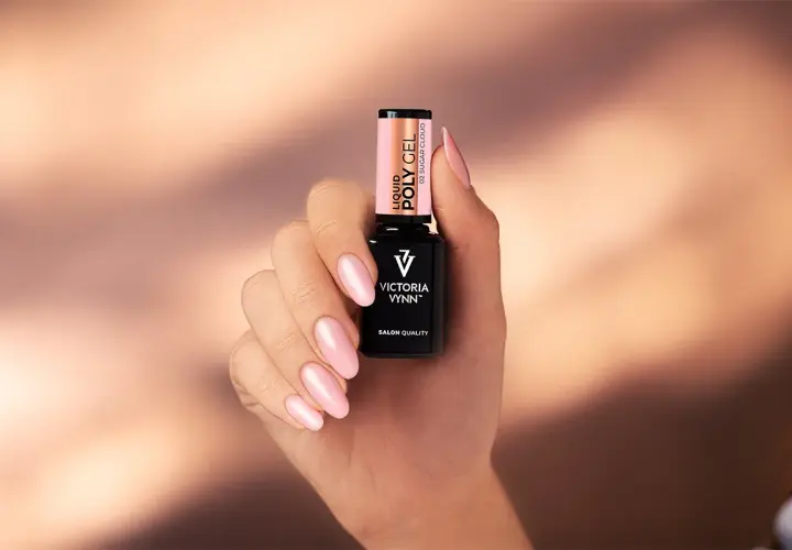 Dłoń z różowymi paznokciami trzyma buteleczkę Liquid Poly Gel Victoria Vynn. To produkt do stylizacji paznokci.