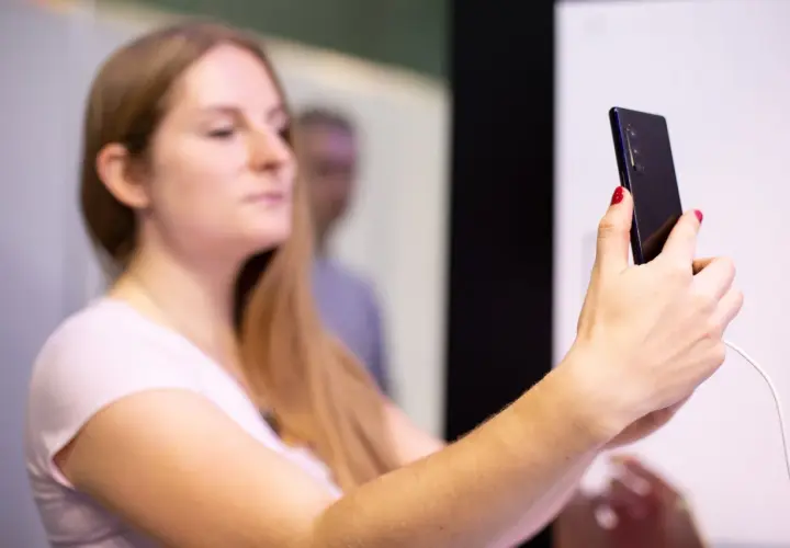 Kobieta z długimi blond włosami trzyma smartfon, na którym widać **aplikację Tuya po polsku**.