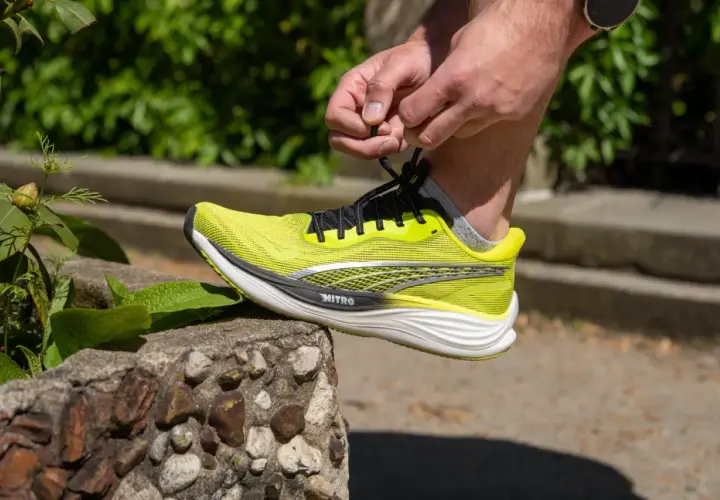 Dłoń wiąże sznurówki jaskrawożółtego buta Puma Deviate Nitro 3, gotowego na bieg.