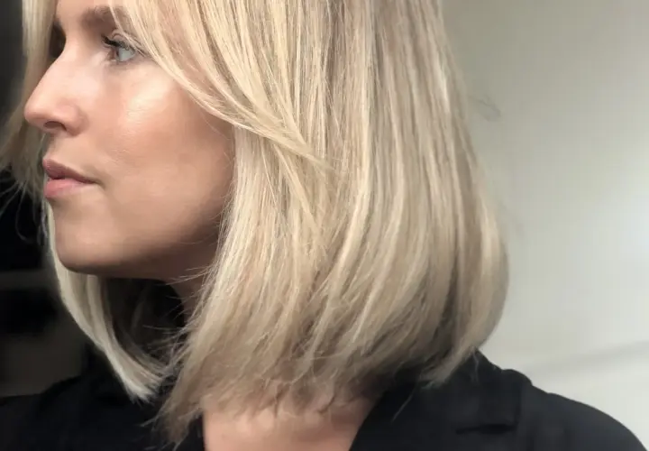 En kvinna med blont hår i en lobklippning, med en naturlig sminkning som framhäver hennes ansiktsdrag. Perfekt för smink tips.