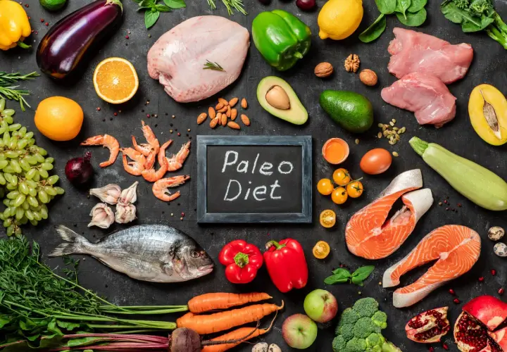 Na czarnej desce z napisem "Paleo Diet" ułożono składniki: ryby, mięso, owoce, warzywa i jajka. Idealny jadłospis dla zwolenników diety jaskiniowców.