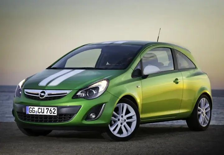 Zielony Opel Corsa D 1.2 benzyna z białymi pasami na masce, zaparkowany na plaży.
