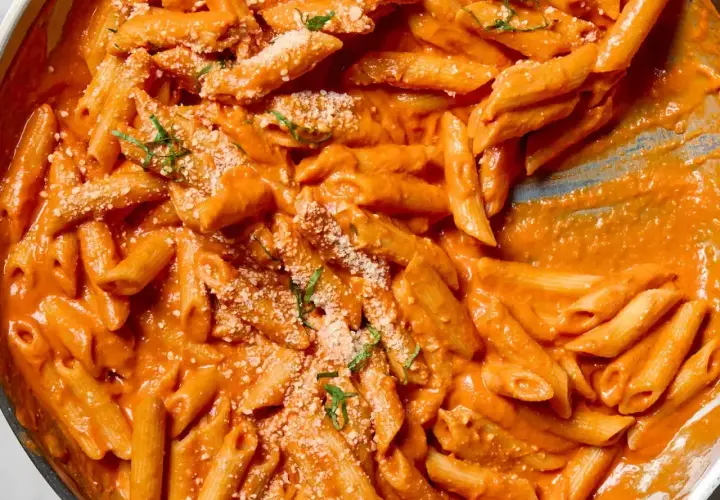 Penne alla vodka w kremowym, pomarańczowym sosie, posypane parmezanem i bazylią.