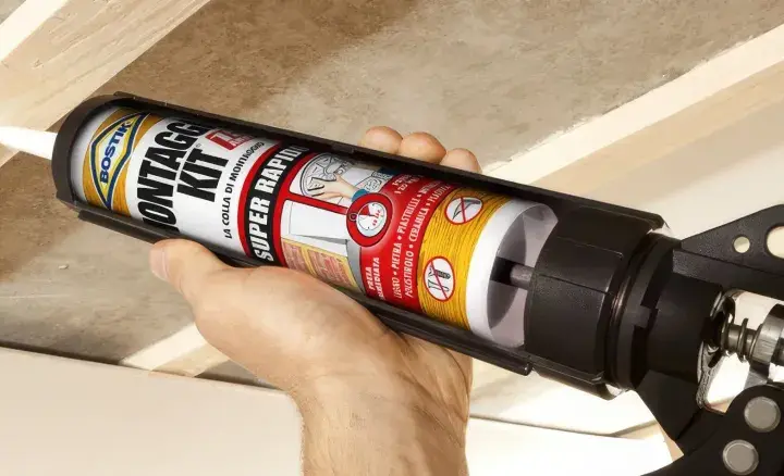 Applicazione di colla per cartongesso antiumido su listelli di legno per un montaggio rapido e sicuro.