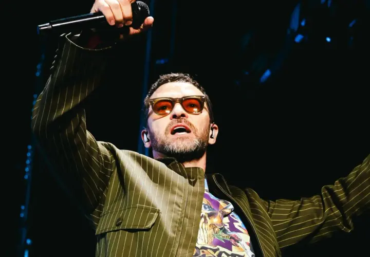 Justin Timberlake w okularach i marynarce w paski śpiewa na koncercie w Polsce.