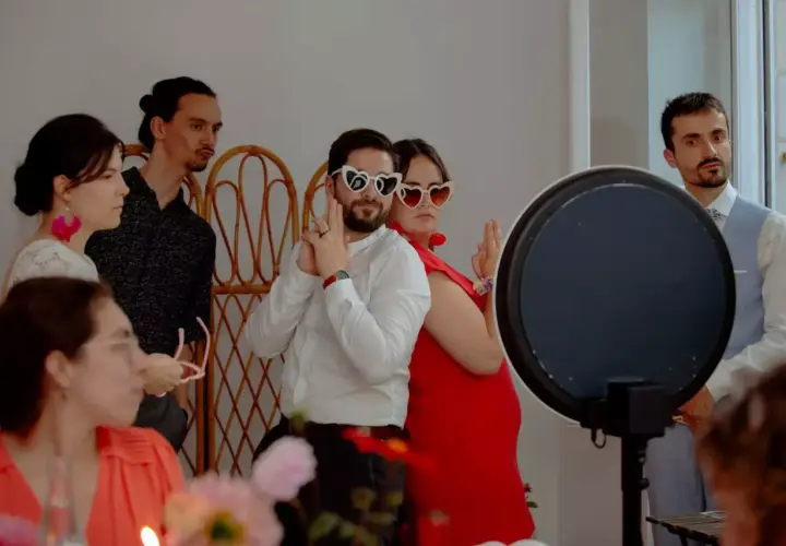 Des invités s'amusent avec des lunettes en forme de cœur lors d'un repas enfant mariage.