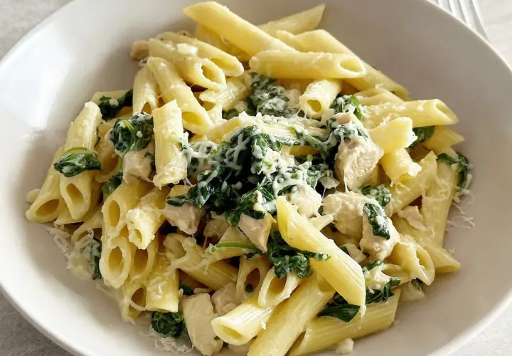 Penne z kurczakiem i szpinakiem w kremowym sosie, posypane parmezanem. Pyszne danie, które zadowoli każdego miłośnika makaronów.