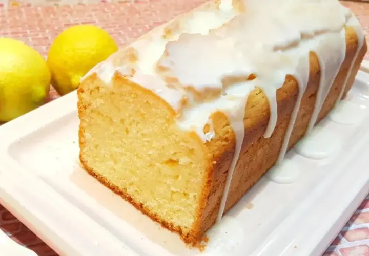 Budín de limón casero con glaseado blanco, acompañado de dos limones frescos. ¡Perfecto para la merienda!