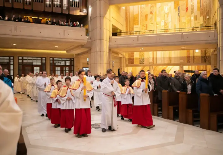 Procesja dzieci niosących świece w kościele. Dziś msza trwa dłużej, bo to uroczystość.