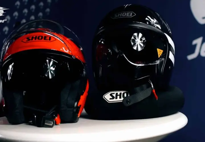 Dwa kaski motocyklowe Shoei: jeden czerwono-czarny, drugi czarny. Oba mają widoczne zapięcie kasku DD.