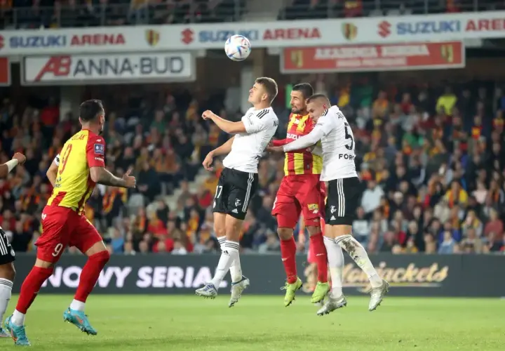 Piłkarze walczą o piłkę w powietrzu. Kibice na trybunach śledzą emocje, jakby oglądali kluczowe ekstraklasa transfery.