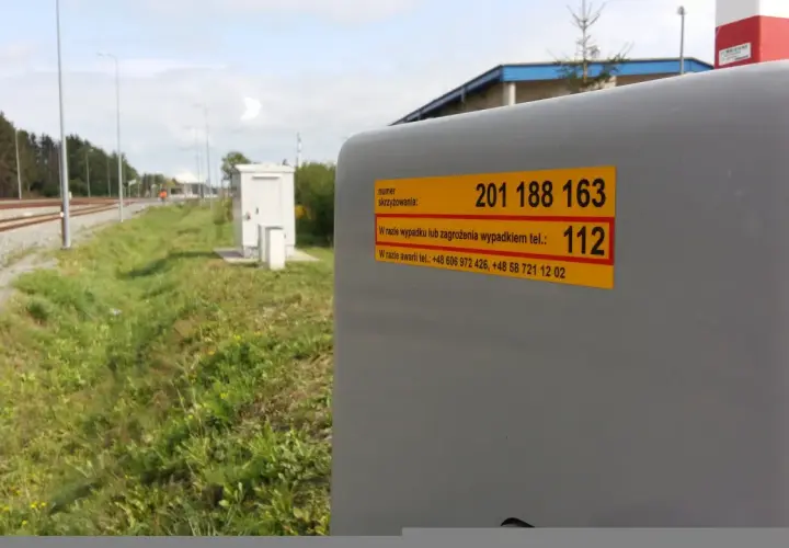 Żółta naklejka plk. z numerem skrzyżowania 201 188 163 i numerem alarmowym 112.