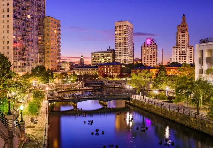 Wieczorny widok na Providence, stolicę najmniejszego stanu USA, Rhode Island. Rzeka otoczona budynkami i zielenią.