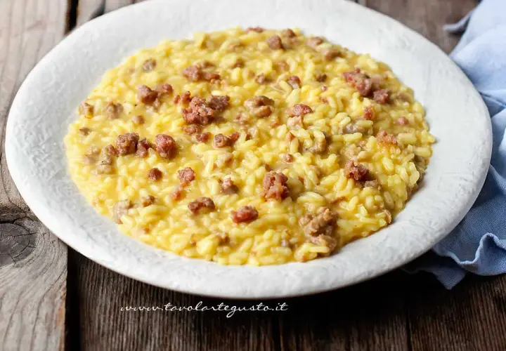 Un cremoso risotto con salsiccia, servito su un piatto bianco, pronto per essere gustato.