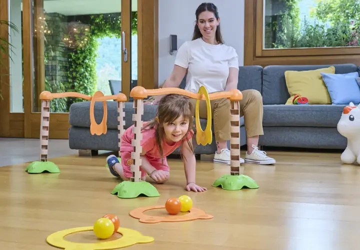 Bambina di 5 mesi esplora un percorso giochi con la mamma. Attività divertente e stimolante per lo sviluppo motorio.
