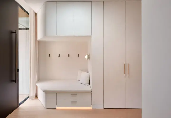 Coin salon moderne avec banquette intégrée, rangements et armoire murale. Le **pose lambris** discret souligne l'espace cosy.