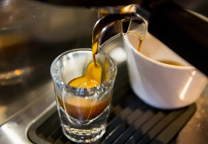 Gorący strumień kawy spływa do szklanki, tworząc idealne espresso. To właśnie taka kawa jest najlepsza!