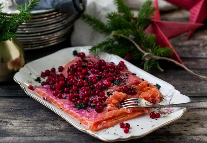 Apelsingravad lax med lingon och dill på ett vackert fat, redo för julbordet.
