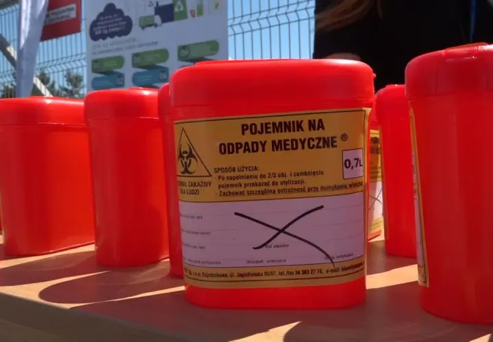 Czerwone pojemniki na odpady medyczne, w tym zużyte igły, czekają na prawidłowe wyrzucenie.