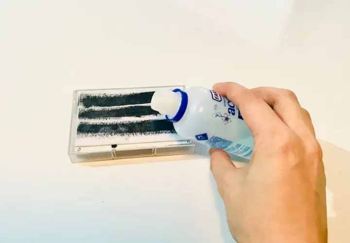 Mano versa liquido da flacone su nastro adesivo per rimuovere colla adesivi.