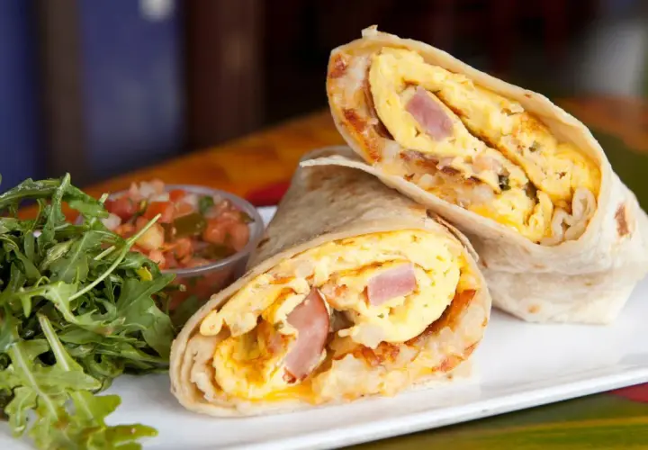 Pyszny omlet z tortillą, jajecznica, szynka i ziemniaki zawinięte w placek. Obok sałatka i salsa.