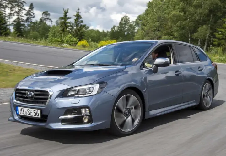 Szary Subaru Levorg na zakręcie drogi, otoczony zielenią.