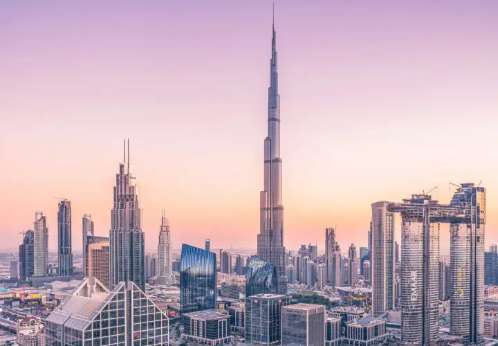 Widok panoramy Dubaju z Burdż Chalifą na pierwszym planie, w blasku zachodzącego słońca.