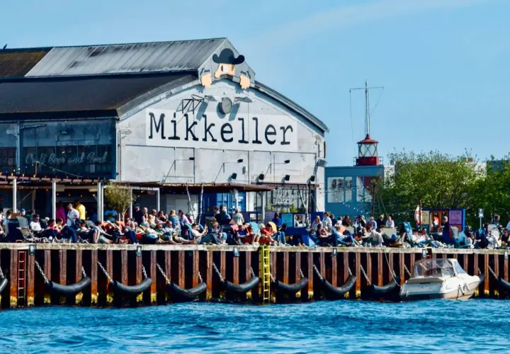 Menschen genießen das Kopenhagen Essen und Craft Beer am Kai vor dem Mikkeller Gebäude.