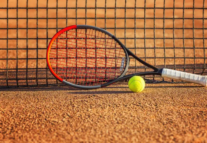 Rakieta tenisowa Wilson Clash i piłka leżą na korcie, gotowe do gry.