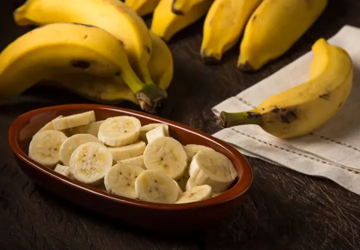 Kawałki banana w misce i cały banan obok. Pomyśl o tym, ile energii dostarcza jeden banan, kalorie to tylko jedna z jego zalet.